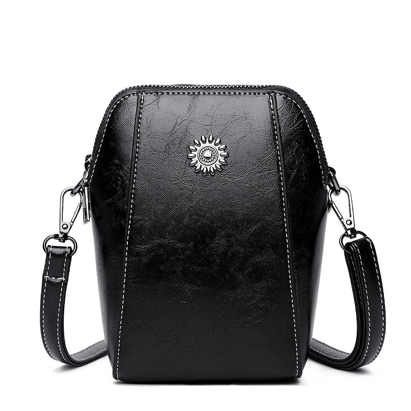 Black mini crossbody handbag with zipper and sunburst emblem