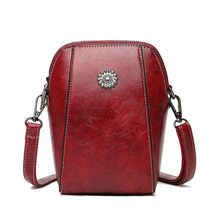 Red mini crossbody handbag with zipper and sunburst emblem