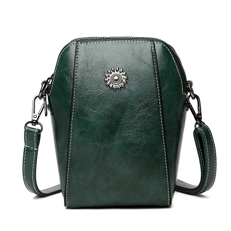 Green mini crossbody handbag with zipper and sunburst emblem