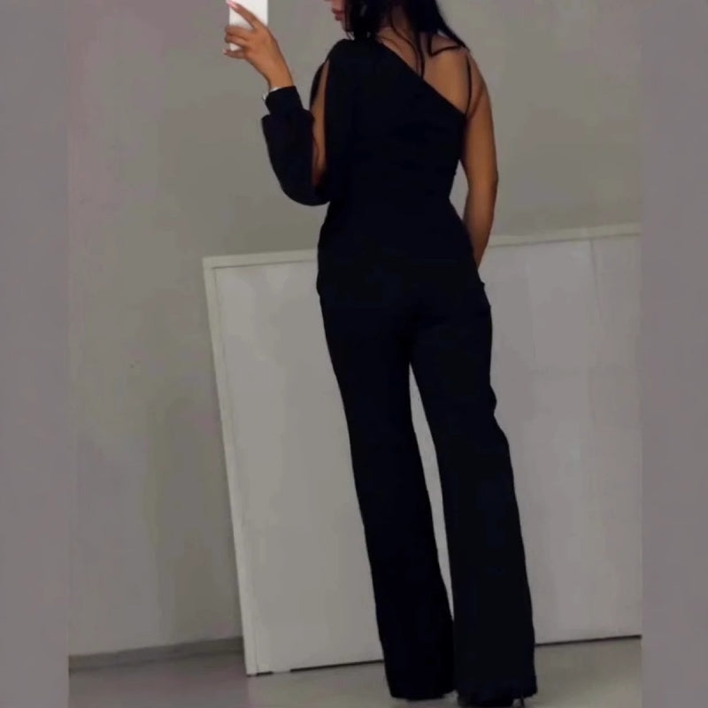 Black one-shoulder flared romper with halter strap, open back, and long wide legs
