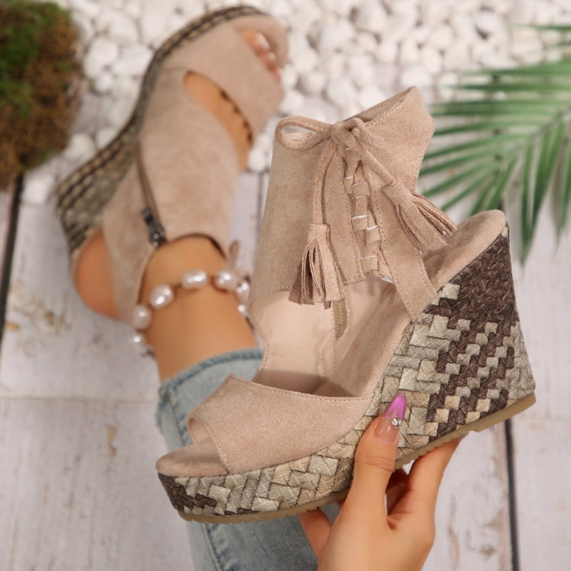 Beige suede wedge sandals with tassel lace-up ankle and patterned platform sole.