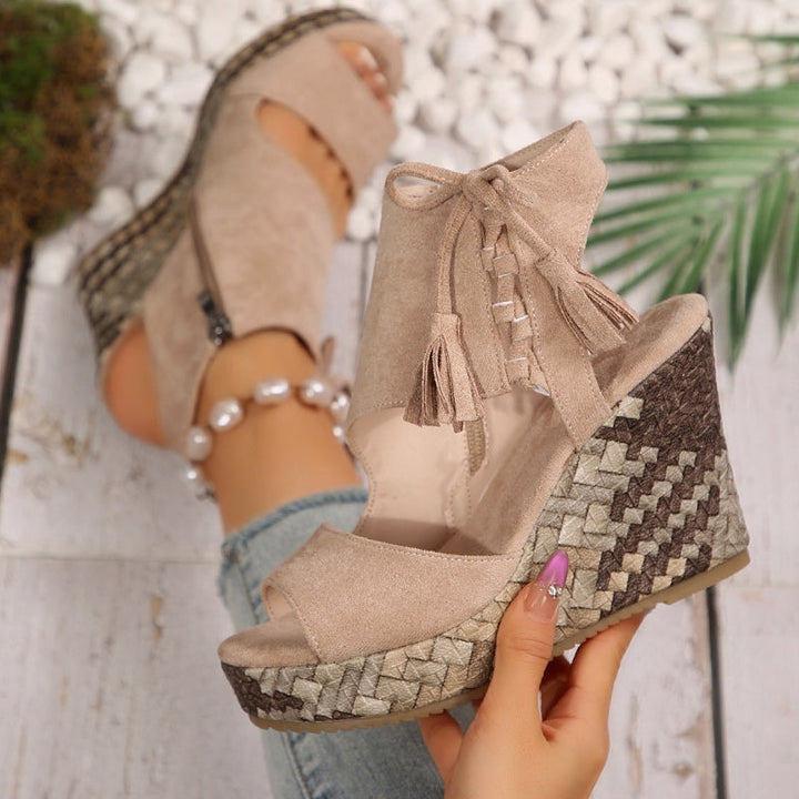Beige suede wedge sandals with tassel lace-up ankle and patterned platform sole.
