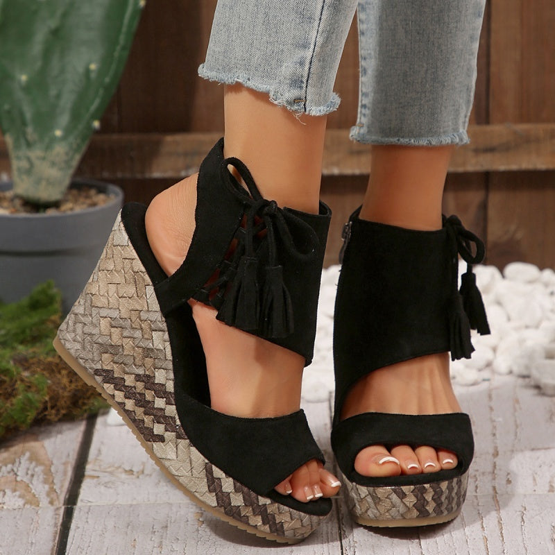 Black suede wedge sandals with tassel ties, peep toe, and patterned platform heel.